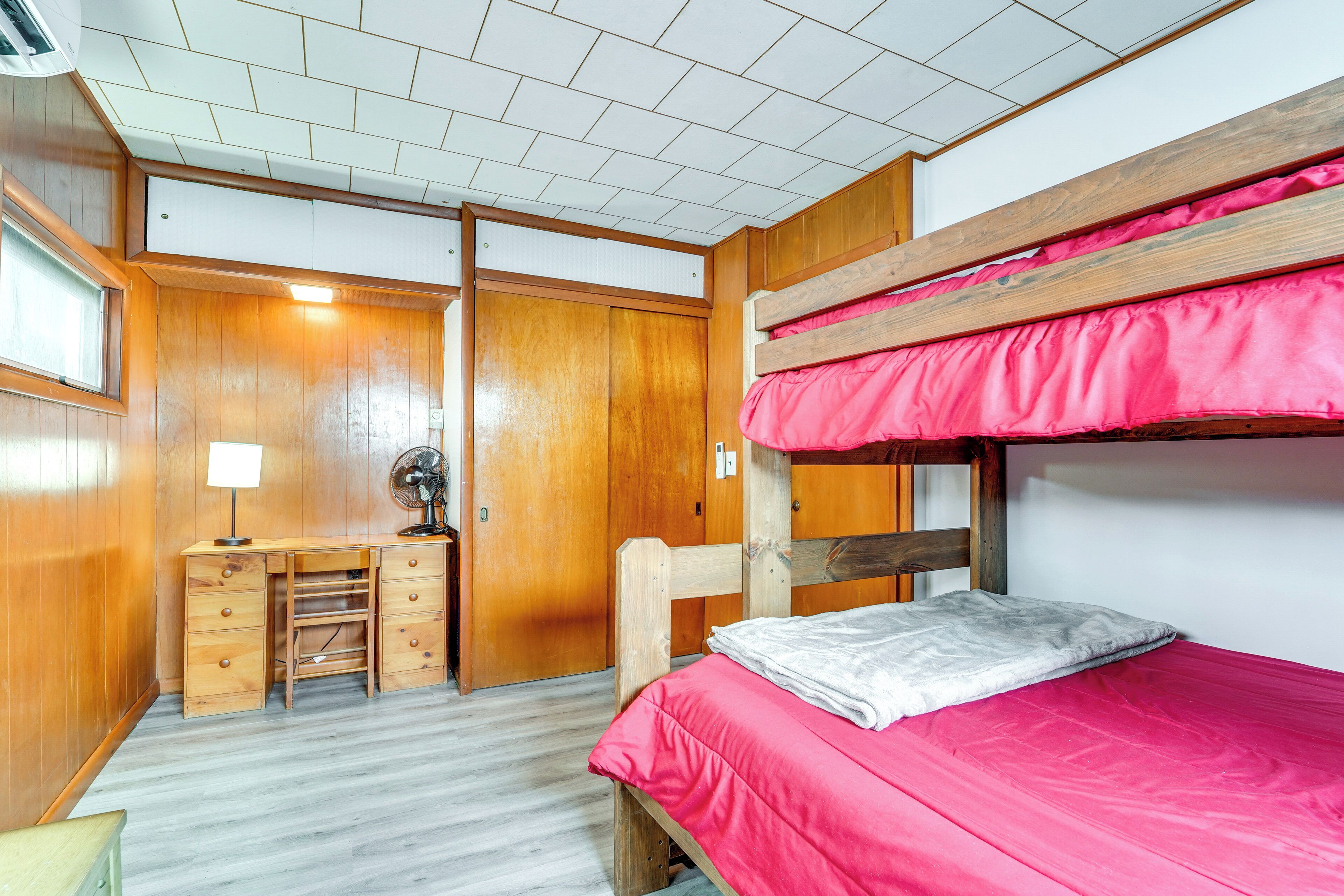A room with a bunk bed, wooden desk, and a wardrobe.