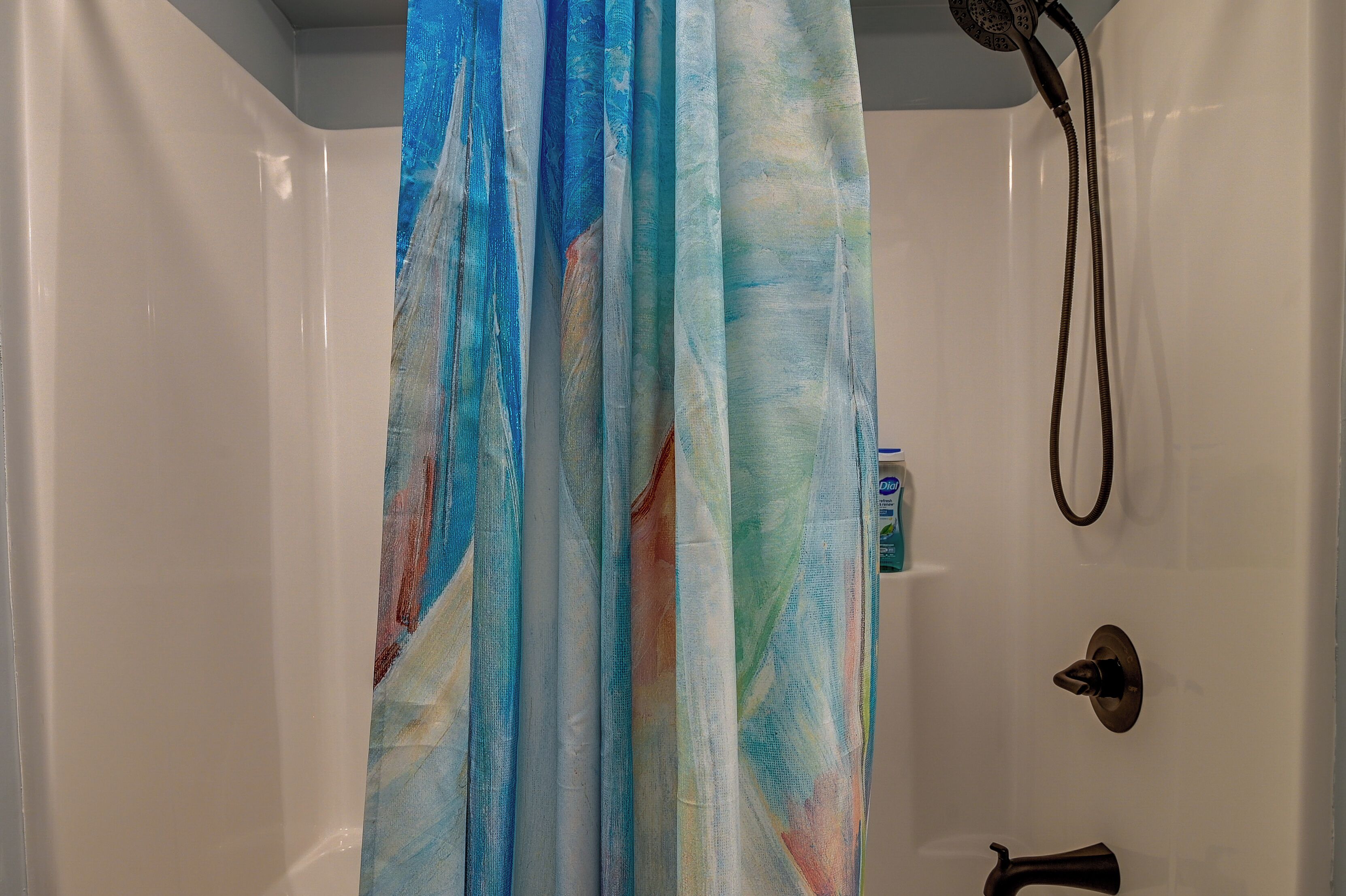 Ein Badezimmer mit Duschvorhang, Duschbrausehandstück und Toilette.
