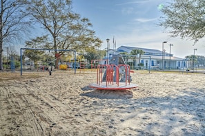 A playground with various play structures, including a red merry-go-round, under a clear sky.