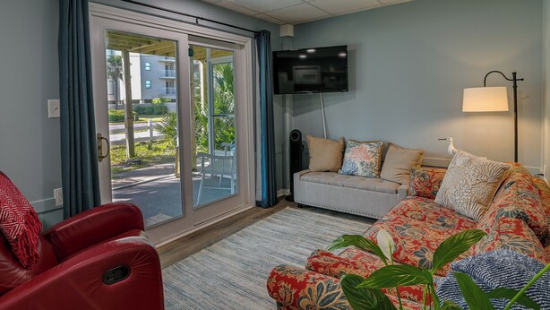A living room with a sofa, a red massage chair, a TV, and a lamp. - 'below Deck' Beach House: Walk to the Ocean! (Murrells Inlet)