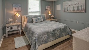 A bedroom with a bed, nightstands, wall art, and a window. - 'below Deck' Beach House: Walk to the Ocean! (Murrells Inlet)