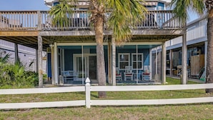 A beachfront house with a covered patio, palm trees, and a white fence. - 'below Deck' Beach House: Walk to the Ocean! (Murrells Inlet)