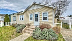 A single-story house with a front porch, a white picket fence, and a small front yard with shrubs.