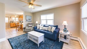 A living room with a blue sofa, a coffee table, a lamp, and a ceiling fan.