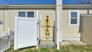 A house with a white garage door, a white fence, and a yellow surfboard hanging on the garage door.