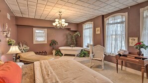 Quarto com duas camas, uma penteadeira, uma cadeira, uma banheira e um candelabro.
