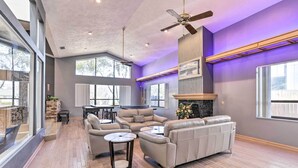 A spacious living room with a fireplace, large windows, and a ceiling fan. - Huge Home w/ Pool Table Near St Pete Beach! (Seminole)