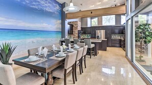 A modern kitchen with dark cabinetry, a brick wall, and a large island. - Huge Home w/ Pool Table Near St Pete Beach! (Seminole)