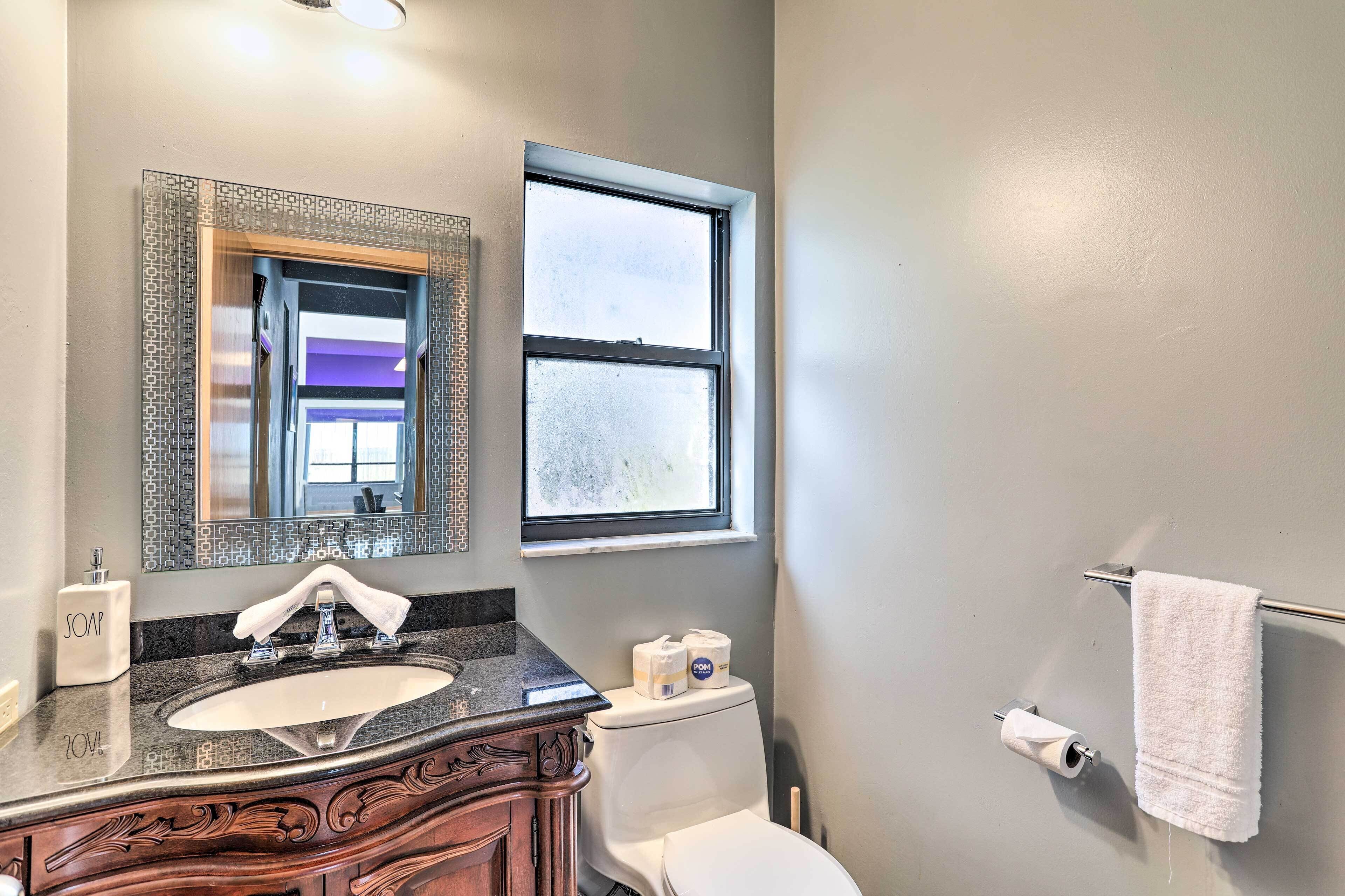 Une salle de bain avec un lavabo, un miroir, des toilettes et une fenêtre.