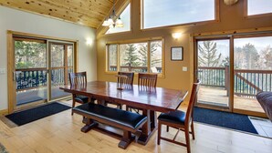 A spacious dining area with a wooden table and benches, large windows, and a view of the outdoors. - Spacious Terry Peak Cabin < 1 Mi to Ski Lift (Lead)