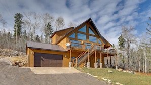A two-story log cabin with a large garage, a balcony, and a stone foundation. - Spacious Terry Peak Cabin < 1 Mi to Ski Lift (Lead)
