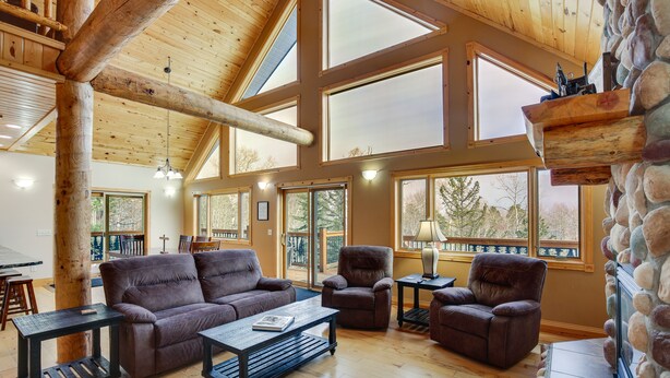 A spacious living room with a high ceiling, large windows, and a stone fireplace. - Spacious Terry Peak Cabin < 1 Mi to Ski Lift (Lead)