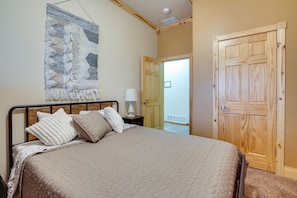 A bedroom with a bed, a wall hanging, and a wooden door.