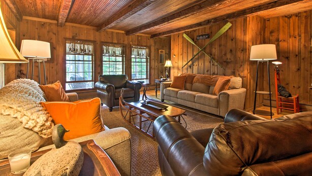A cozy log cabin interior with a fireplace, leather sofas, and a dining table. - Vintage Schroon Lake Farmhouse w/ Private Beach! (Schroon Lake)