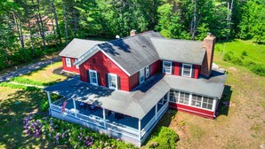 A two-story house with a porch, a chimney, and a well-maintained garden. - Vintage Schroon Lake Farmhouse w/ Private Beach! (Schroon Lake)