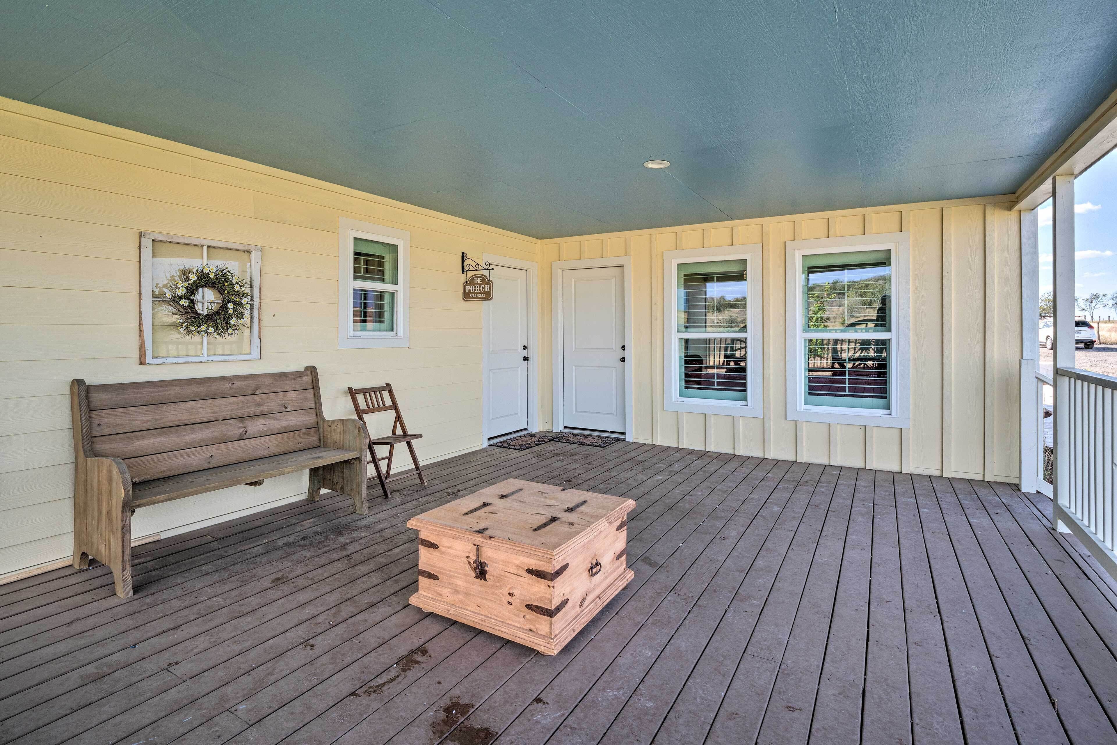 A covered porch with a wooden bench, a small table, and a wooden chest.