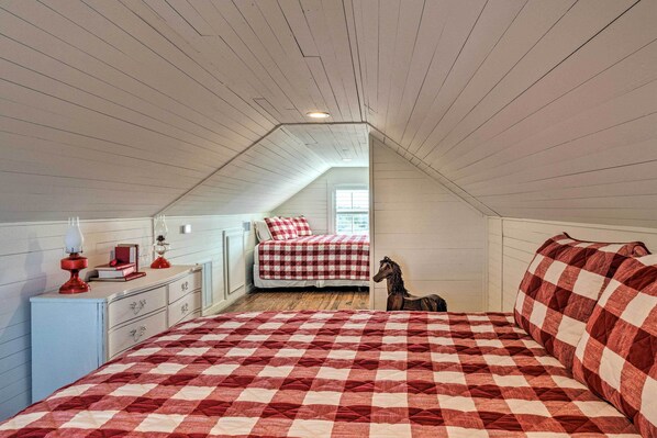 Une chambre à coucher avec une couvre-lit à carreaux, une commode, une lampe et une figurine de cheval.