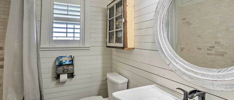 A bathroom with a toilet, sink, and window with blinds.
