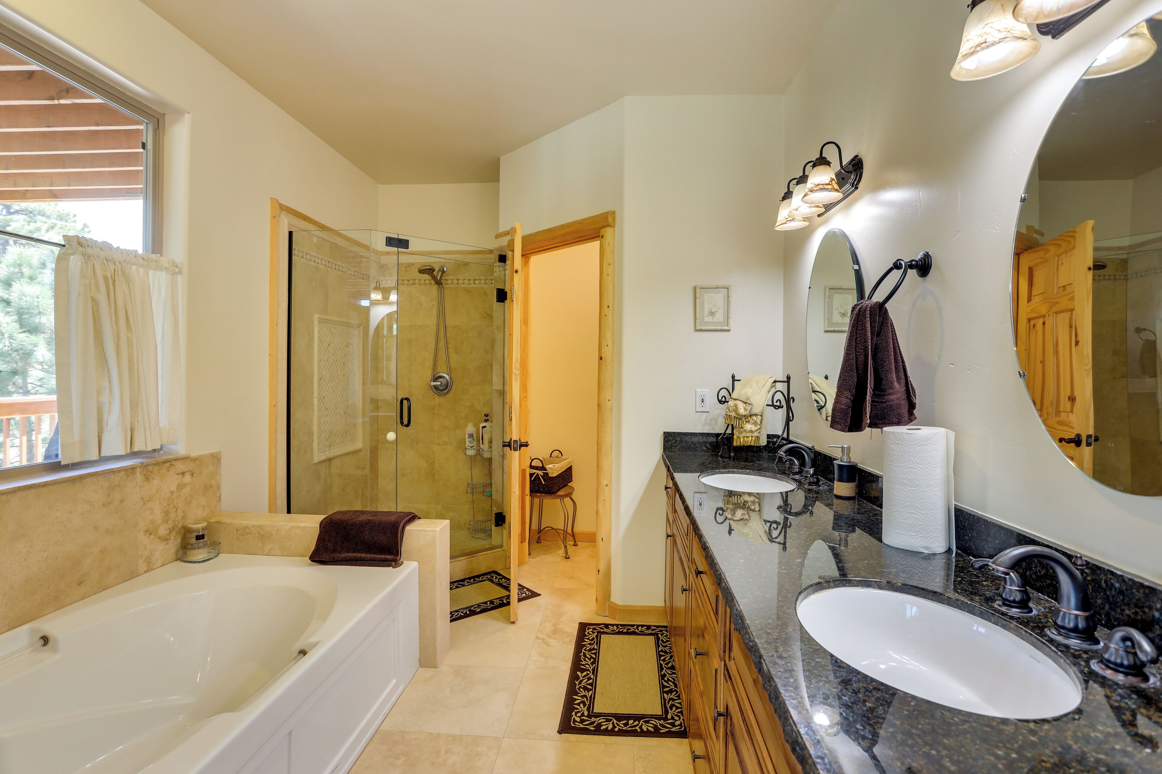 A bathroom with a bathtub, two sinks, a large mirror, and a shower area.