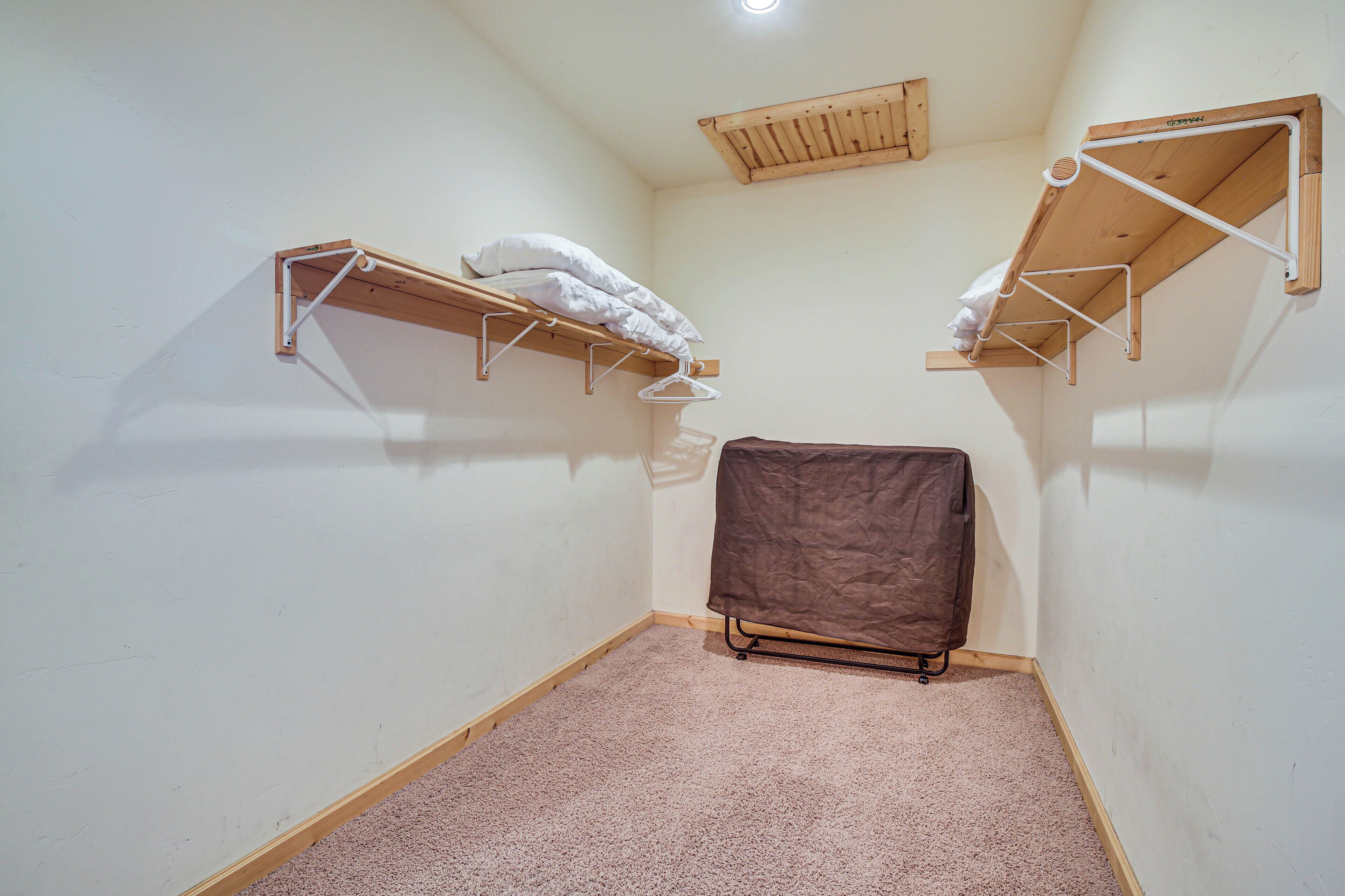 A small, carpeted room with two wooden shelves against the walls, one with a white pillow and the other with a brown cover.