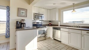 A kitchen with white cabinets, stainless steel appliances, a window with a view, and a pendant light. - Historic Hoopersville Getaway on Chesapeake Bay! (Fishing Creek)