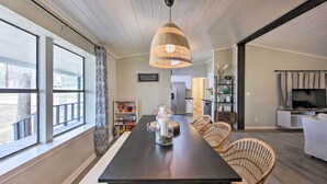 A modern dining area with a dark wooden table, wicker chairs, and a hanging light fixture. - Lake View & Decks: Pet-friendly Mabank Home (Mabank)