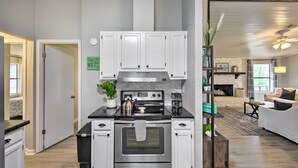A modern kitchen with white cabinets, a stainless steel stove, and a black countertop. - Lake View & Decks: Pet-friendly Mabank Home (Mabank)