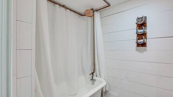 A bathroom with a white bathtub, a wooden wall-mounted towel rack, and a white shower curtain.