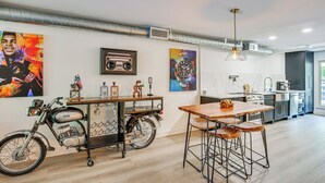 Uma cozinha moderna com área de jantar, exibindo uma motocicleta, banquetas de bar e obras de arte nas paredes.