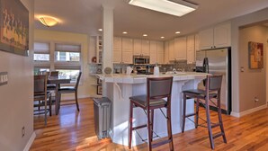 A modern kitchen with a central island, bar stools, and built-in appliances. - Flagstaff Townhome w/ View, Country Club Amenities (Flagstaff)