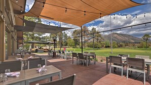 An outdoor patio area with tables and chairs, a covered seating area, and a view of a golf course and mountains in the background. - Flagstaff Townhome w/ View, Country Club Amenities (Flagstaff)