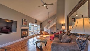 A spacious living room with hardwood flooring, a glass coffee table, a gray sofa, and a fireplace. - Flagstaff Townhome w/ View, Country Club Amenities (Flagstaff)
