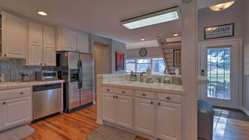 A kitchen with white cabinets, stainless steel appliances, and a view of the outdoors.