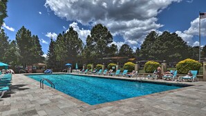 A swimming pool with lounge chairs and umbrellas, surrounded by trees and a clear sky. - Flagstaff Townhome w/ View, Country Club Amenities (Flagstaff)