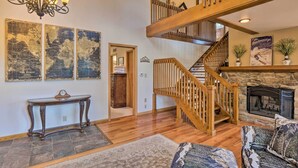 A spacious living room with a wooden staircase, a fireplace, and a console table.