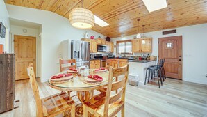A spacious kitchen with wooden cabinets, a central island, and a dining area with a round table and chairs. - Strawberry Hideaway in the Pines w/ Hot Tub! (Pine)