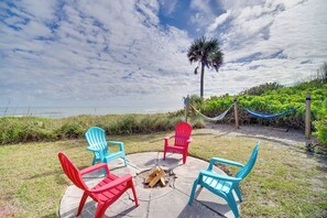 A patio with four Adirondack chairs, a fire pit, and a hammock. - Beachfront Home Fire Pit Hammock Lots of Amenities (Indialantic)