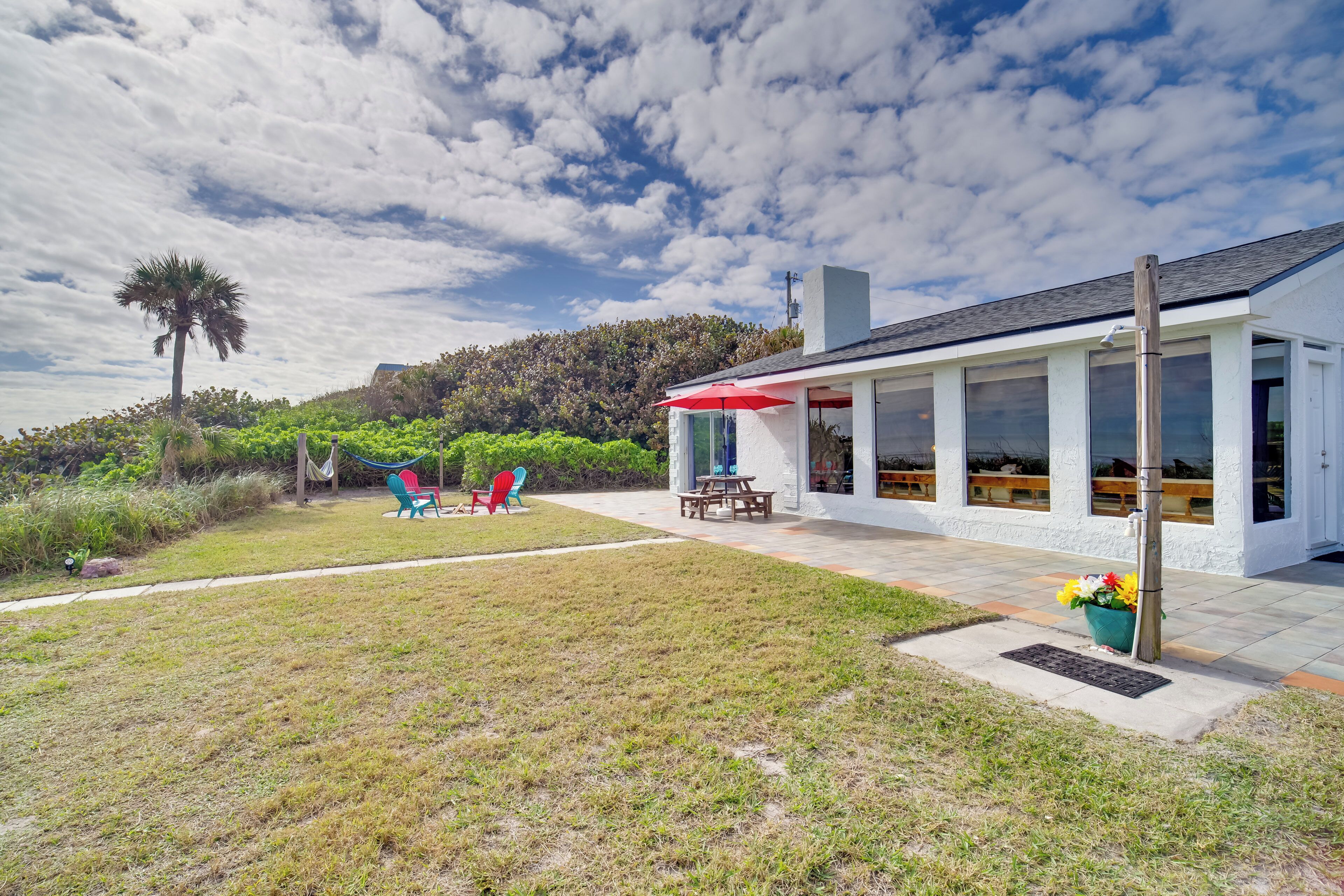 A modern house with a covered patio, a hammock, and a small garden.