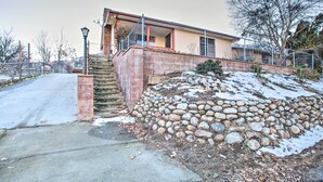 A two-story house with a stone retaining wall, a covered porch, and a staircase leading to the entrance.