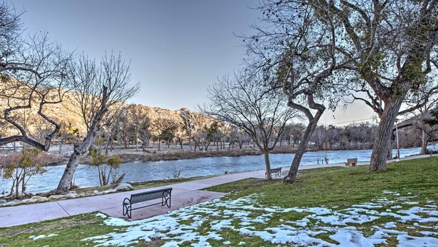 A park with a bench, a river, and trees.