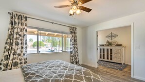A bedroom with a bed, a ceiling fan, a window with curtains, a cabinet, and a rug. - Upscale Sun City Home on South Golf Course (Sun City)