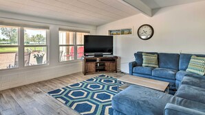 A living room with a TV, blue sofa, and a patterned rug. - Upscale Sun City Home on South Golf Course (Sun City)