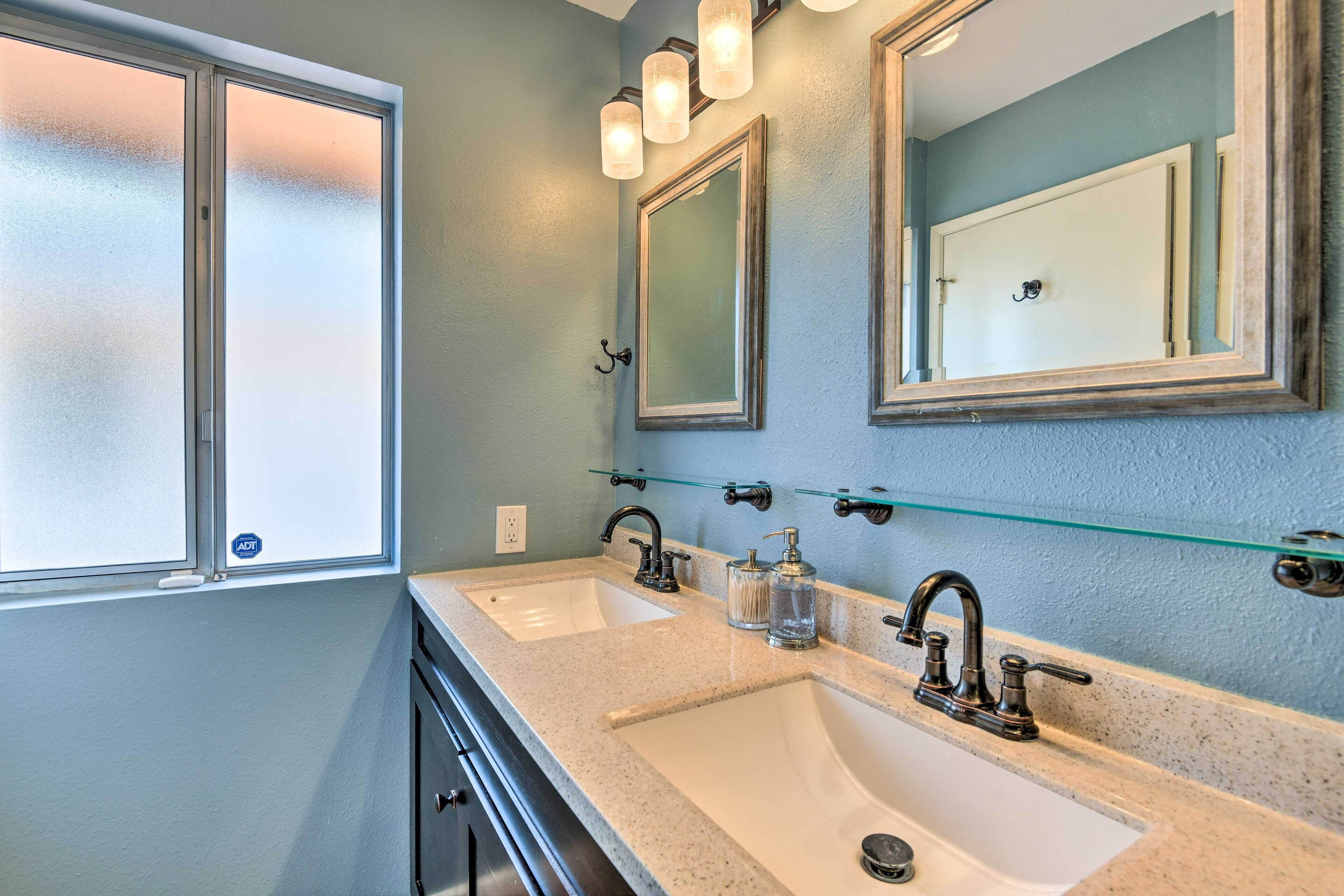 A bathroom with two sinks, frosted glass windows, and a mirror with a light fixture above.
