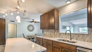 A modern kitchen with a large island, wooden cabinets, a built-in oven, and a window providing natural light. - Upscale Sun City Home on South Golf Course (Sun City)