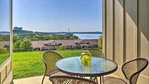 A balcony with wicker chairs and a glass table, overlooking a green landscape and a body of water. - Branson Condo w/ Table Rock Lake Views, Near Strip (Branson)