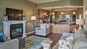 A living room with a fireplace, sofa, and coffee table, a kitchen with wooden cabinets, and a dining area with pendant lights. - Branson Condo w/ Table Rock Lake Views, Near Strip (Branson)