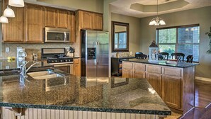 A kitchen with granite countertops, stainless steel appliances, wooden cabinets, and pendant lighting. - Branson Condo w/ Table Rock Lake Views, Near Strip (Branson)