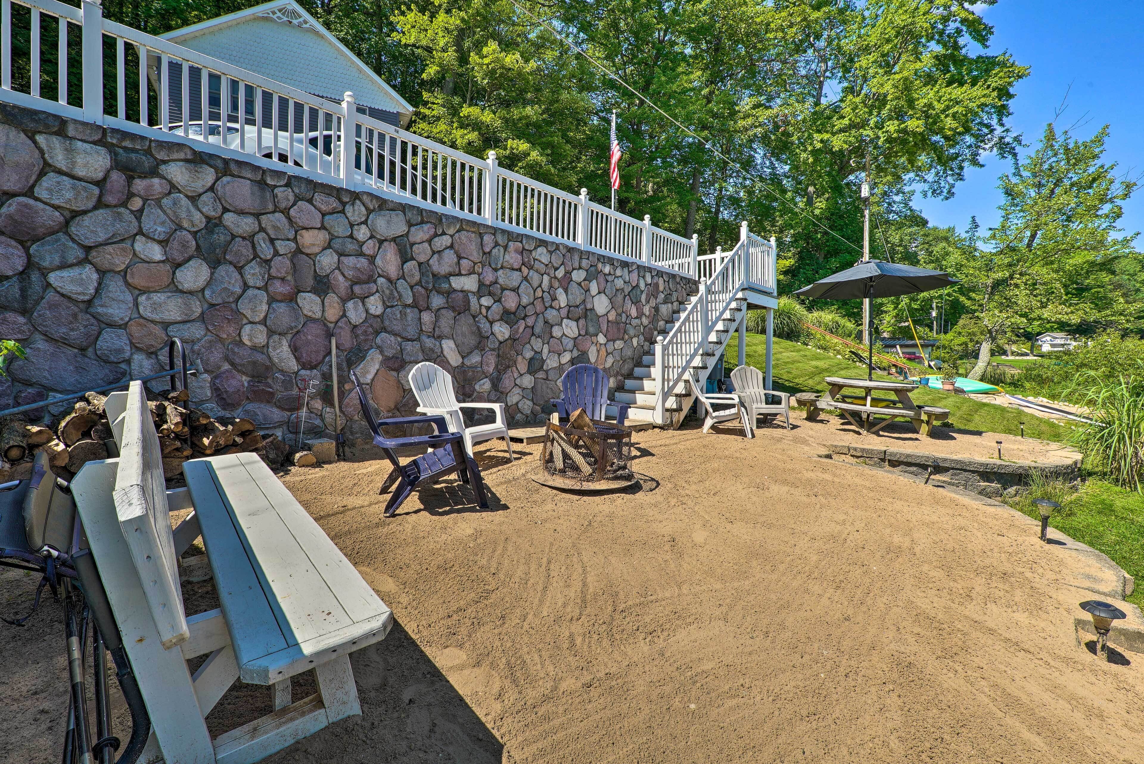 A patio area with Adirondack chairs, a fire pit, and a picnic table.