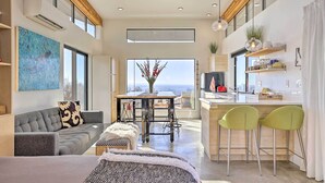 A modern living space with a sofa, a dining table, and a kitchen area with bar stools. - Luxe, Modern Studio w/ Sweeping City Views! (Boise)