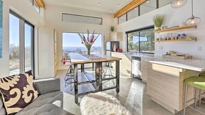 A modern kitchen with a large island, wooden beams, and a city view. - Luxe, Modern Studio w/ Sweeping City Views! (Boise)